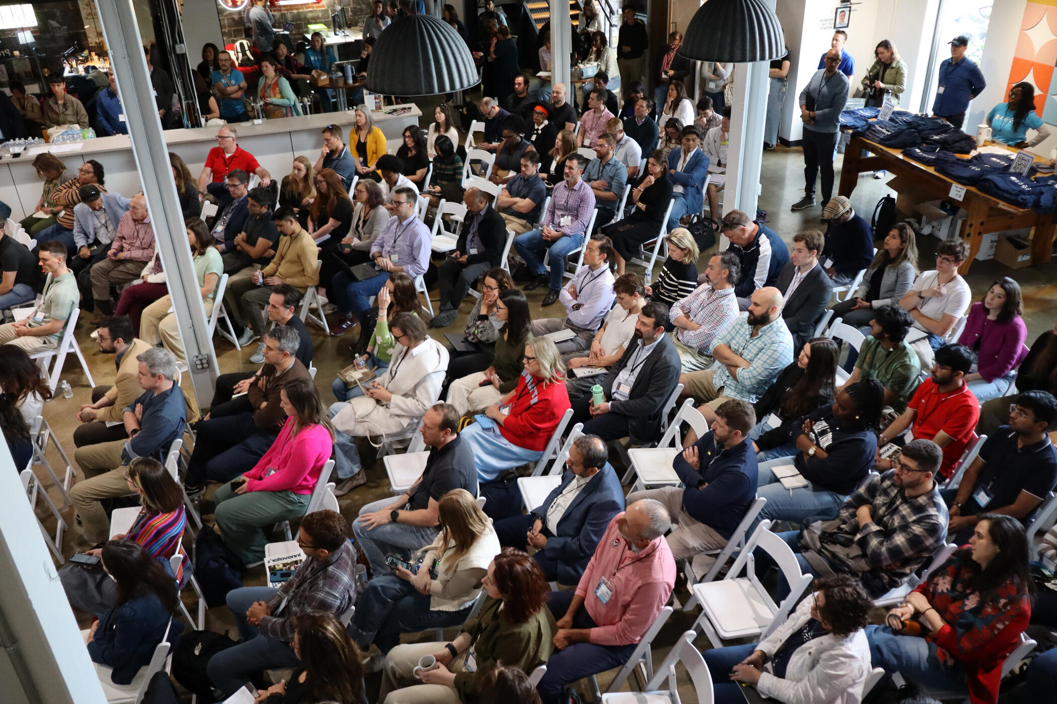 a large group of people sitting in an audience listening to a speaker